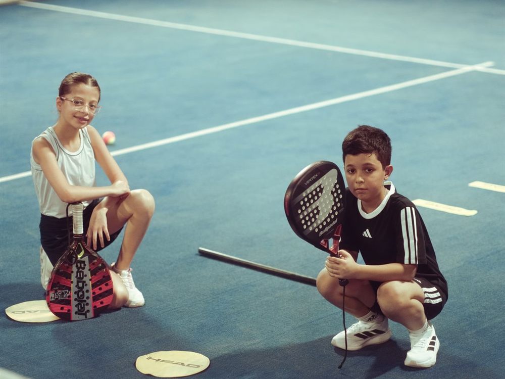 Dos niños con palas de pádel en una pista indoor (foto de stock)